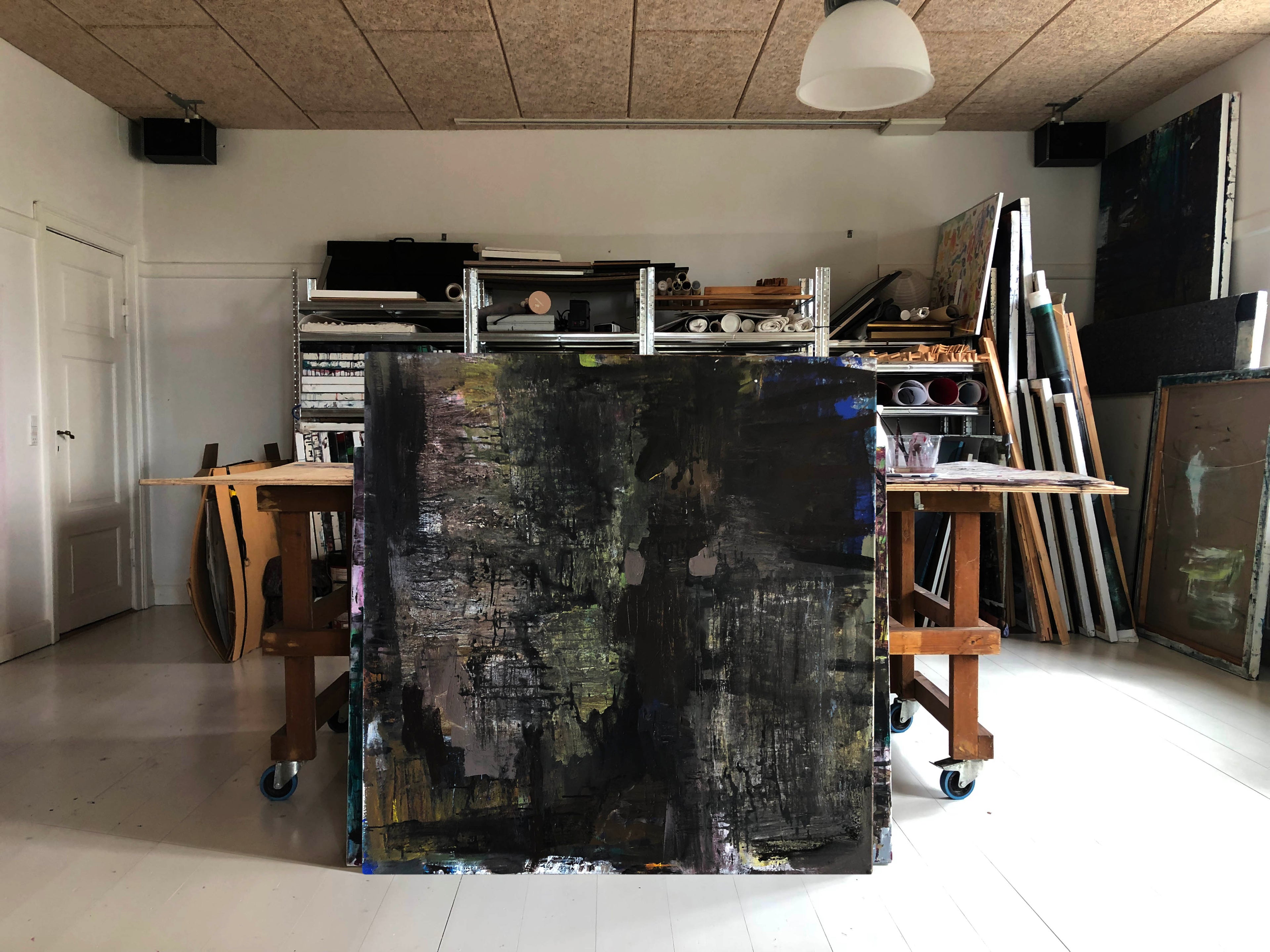 Abstrakt mørk kunst af Peter Ejlerskov i lyst atelier med malerier.
