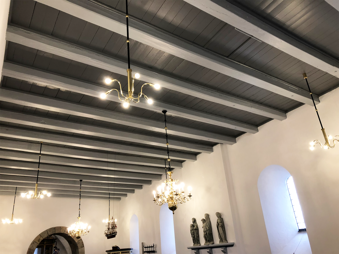 Kirkeudsmykning af Mammen Kirke af Peter Ejlerskov med lysekroner og bjælkeloft.