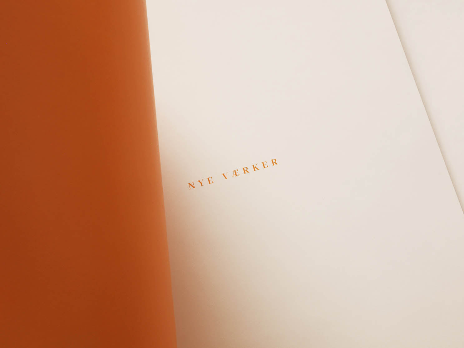Bogen Nye Værker med kunst af Peter Ejlerskov, vist med orange og hvide sider.
